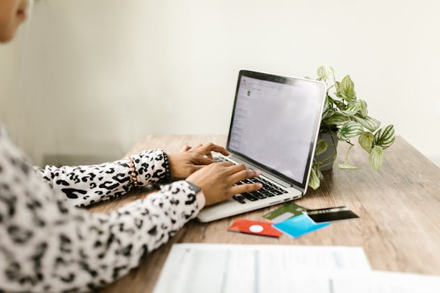 person typing on a laptop with credit card next to them